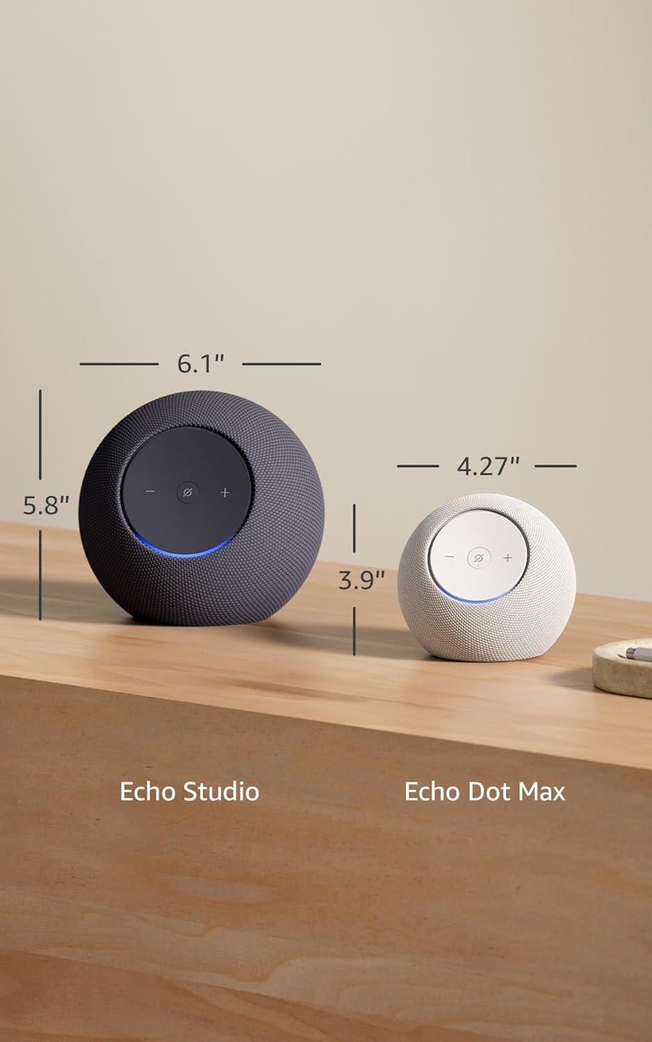 Echo Studio and Echo Dot Max smart speakers placed on a wooden table showing size dimensions comparison.